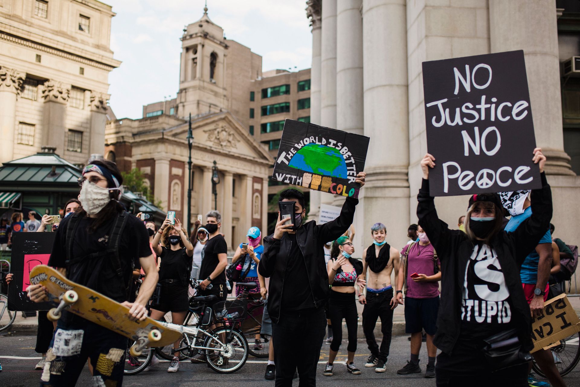 A diverse group of protesters in an urban setting holding signs advocating for justice and solidarity.